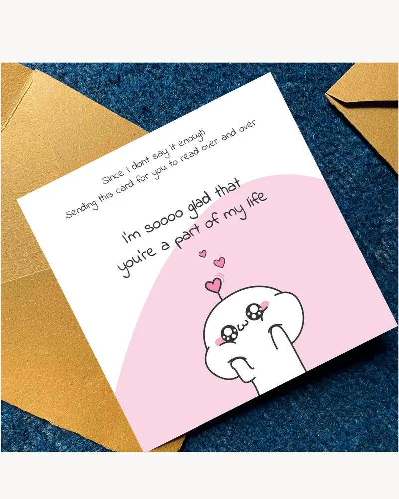 A white greeting card with pink details, featuring a cartoon character and the text "I'm soooo glad 