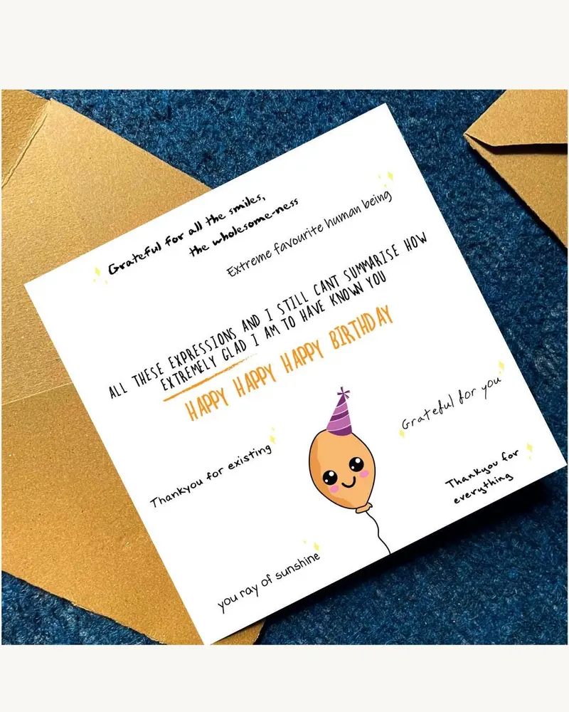 A white birthday card with handwritten text and a cartoon balloon illustration. The card includes ph