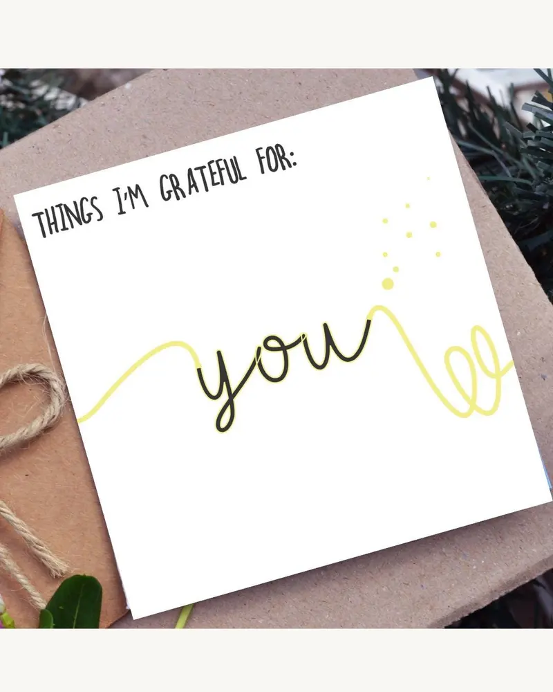 A white greeting card with the words "THINGS I'M GRATEFUL FOR: YOU" in black script. A yellow line d
