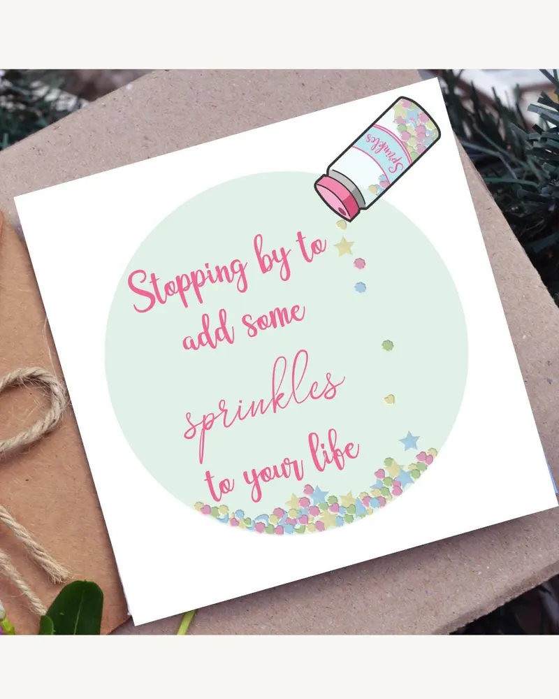 A greeting card with the text "Stopping by to add some sprinkles to your life" in pink script. The c