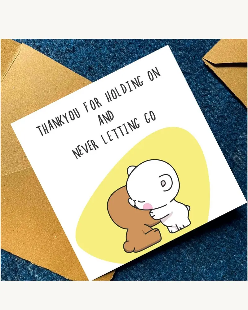 A greeting card with the text "THANKYOU FOR HOLDING ON AND NEVER LETTING GO". The card features a ca