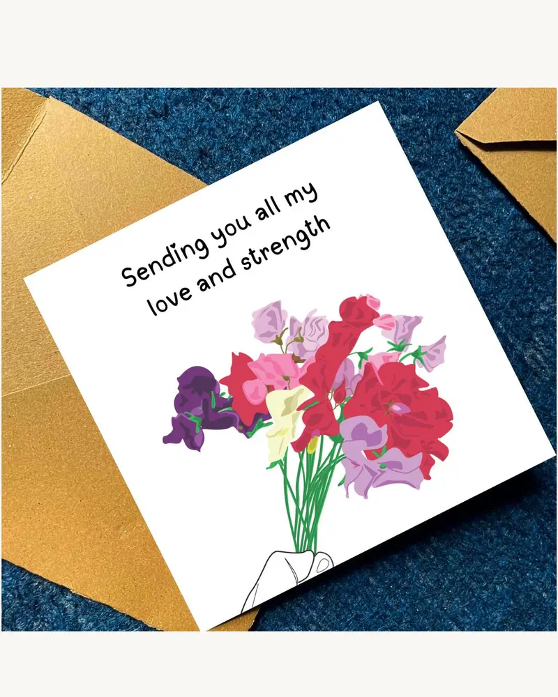 A white greeting card with the text "Sending you all my love and strength" and a colourful floral bo