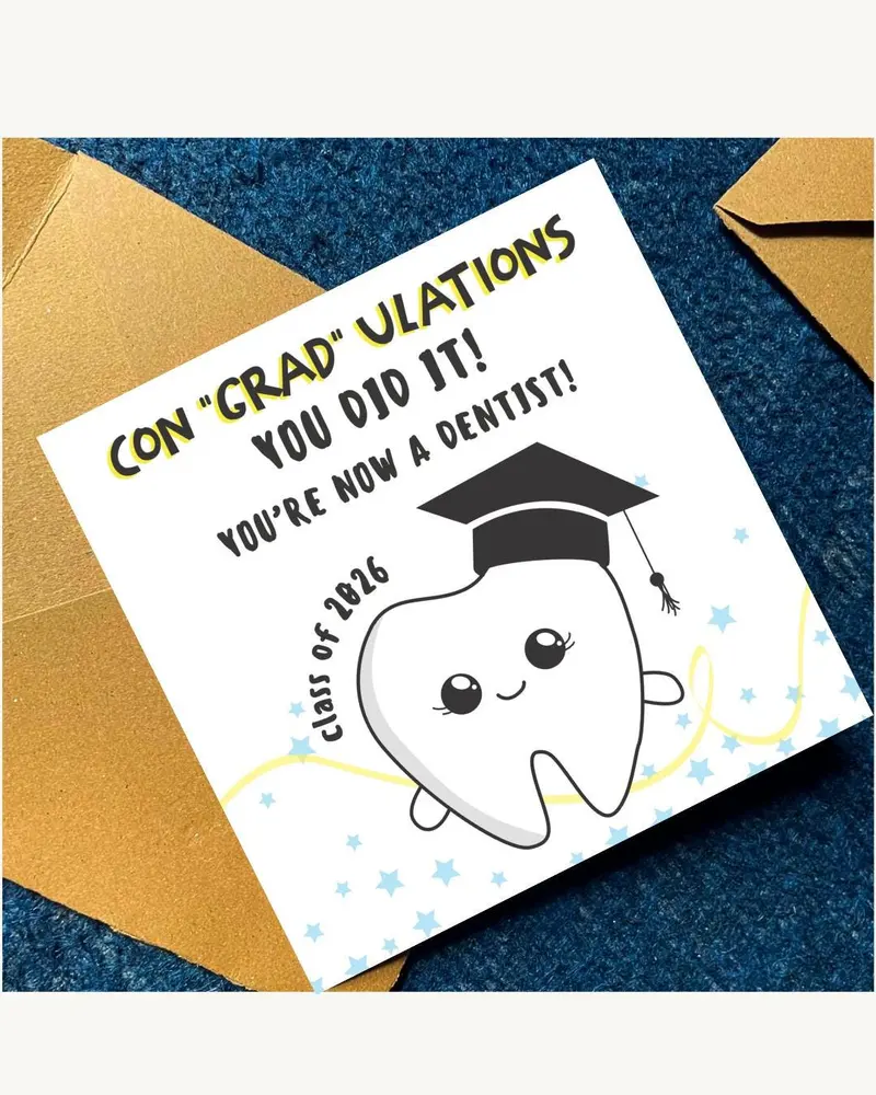 A white graduation card with the text "CON 'GRAD' ULATIONS YOU DID IT! YOU'RE NOW A DENTIST!" in bla