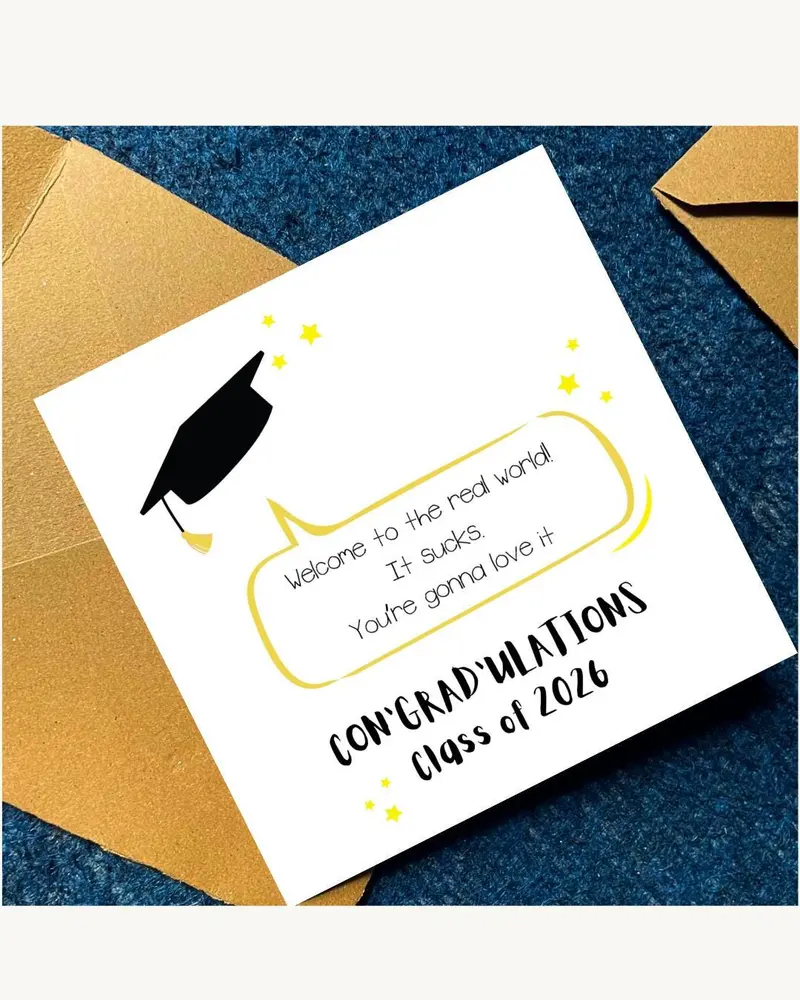 A graduation card with a black mortarboard illustration and the text "Welcome to the real world! It 