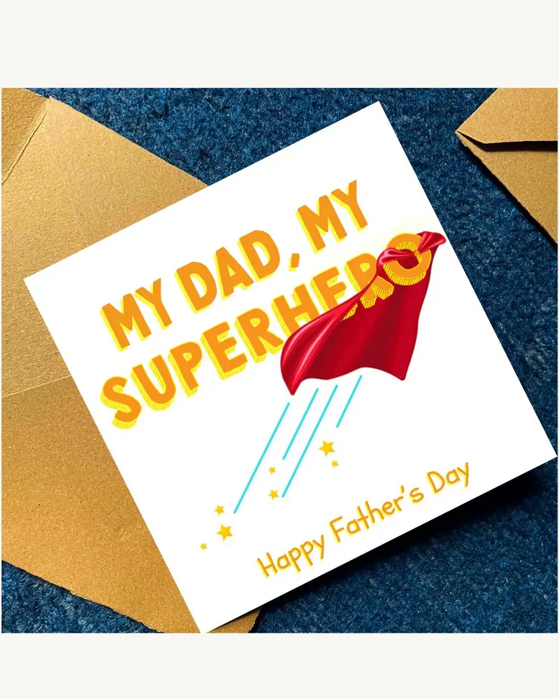 A square greeting card with a white background featuring the yellow text MY DAD, MY SUPERHERO. A red