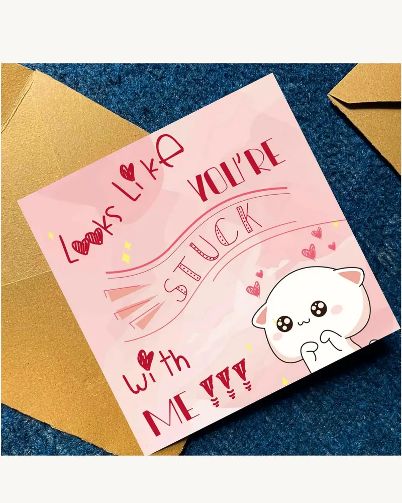 A square greeting card with a light pink background featuring a cartoon white cat with large black e