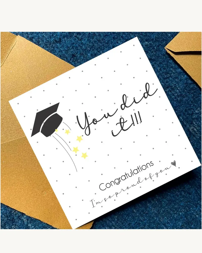 A square white greeting card with a black graduation cap icon, yellow stars, and grey dots. The text